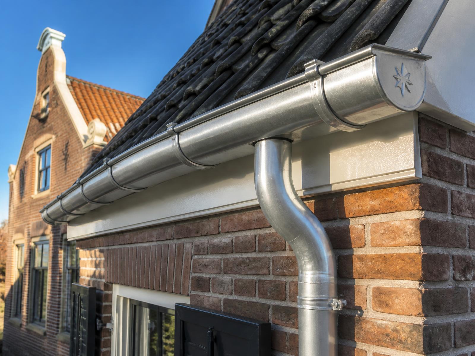 Vakkundig gefelste zinken goot langs een dakrand met natuurleien